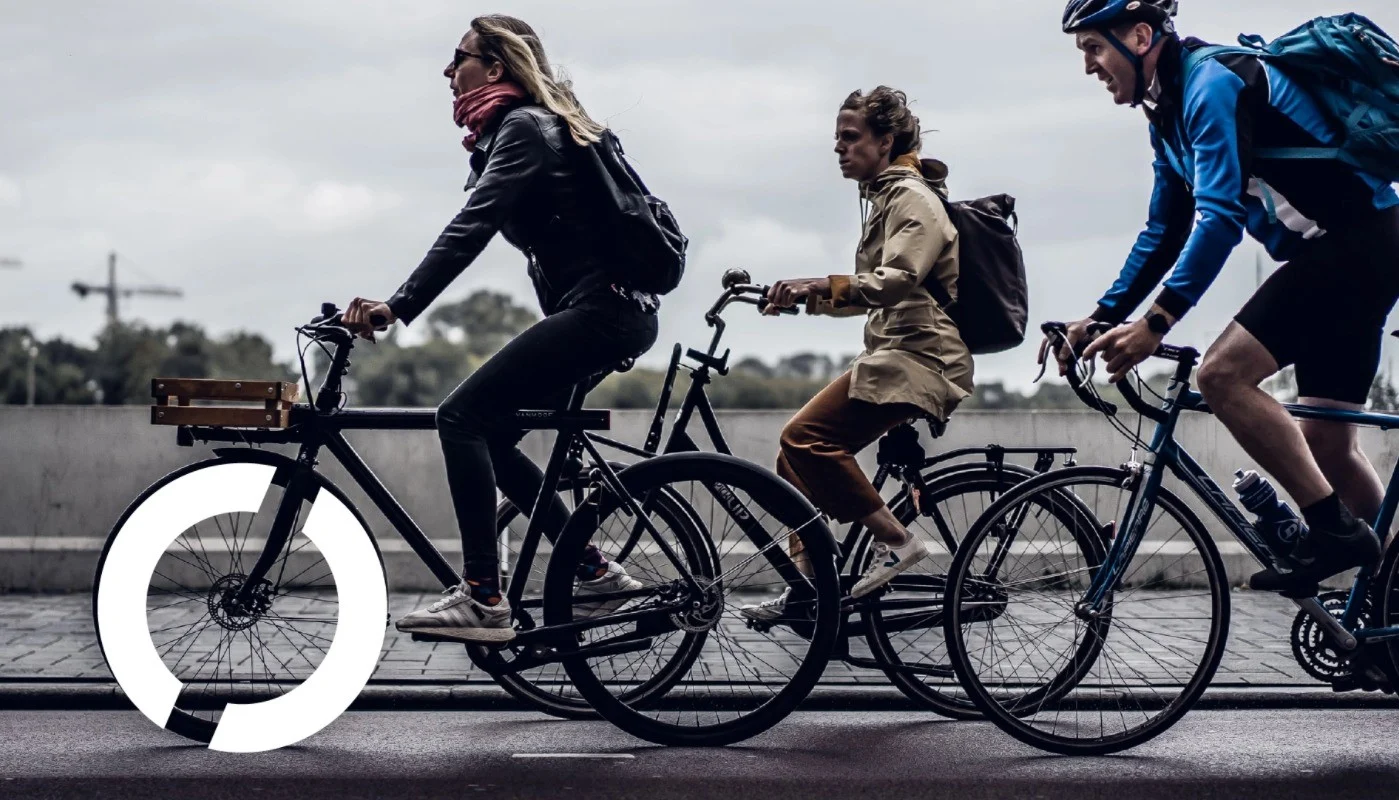 people cycling on bikes, with the tranzparent circular logo around one of the wheels